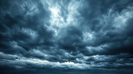 Dramatic stormy skies fill the horizon with shades of gray and blue as dark clouds gather for an impending downpour over the ocean near a coastal area during twilight