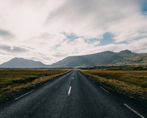 Scenic road leading to dramatic mountains under moody skies in Snæfellsnes Peninsula, West Iceland.