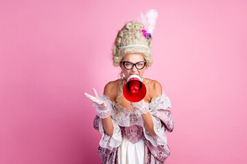 Young woman in vintage royal costume sharing message using a megaphone on pink background
