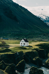 Scenic view of a white house on rugged cliffs with Snæfellsjökull glacier in the background, Arnarstapi, Snæfellsnes Peninsula, West Iceland.