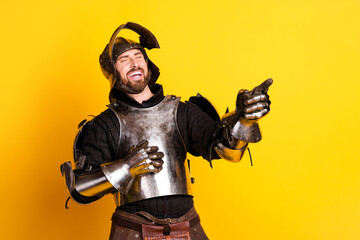 Fototapeta premium Young Man Dressed as a Medieval Knight Smiling on Bright Yellow Background