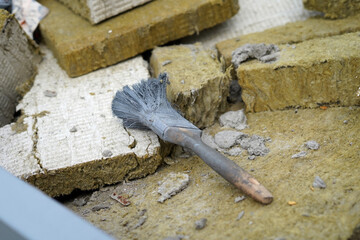 A used and damaged paintbrush. It is frayed and stiff from the gray paint.