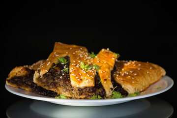 Crispy puff pastries with mushroom filling and sesame seeds, isolated on black background