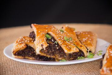 Crispy puff pastries with mushroom filling and sesame seeds, isolated on black background