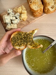 Enjoying fresh bread with pesto and cheese at a cozy kitchen table