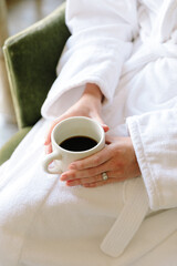 Relaxing morning ritual of enjoying coffee in a cozy robe while seated in a comfortable chair