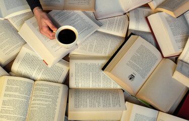 Obraz premium Female young girl hands holding cup hot coffeek on open ancient old books