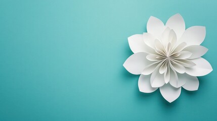 A white paper flower placed on a pastel teal background with a clean, empty area for text or graphics on the side