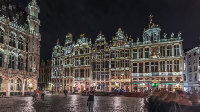 Night hyperlapse of the illuminated Grand Place Guilds facade in Brussels, Belgium. Historic art guild associations in Baroque architecture timelapse, with people walking on the UNESCO-listed square