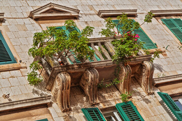 Old windows and balconies in old stone wall with plants
