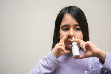 Primary school age girl sprays nasal spray into her nose