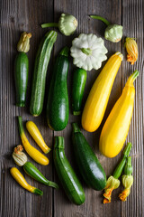 Different kind zucchini, pattypan squash and zucchini flowers on rustic wooden table. Aesthetic...