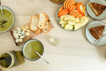 Fresh and healthy meal with green soup and seasonal fruits on a wooden table