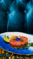 Salmon tartare decorated with flowers on a blue plate