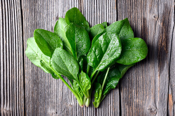 Bunch of fresh green spinach on rustic wooden table close up. Organic spinach greens top view. Food...