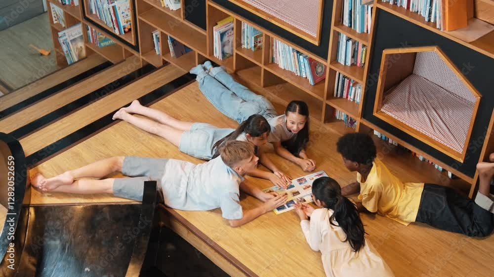 Poster group of diverse children lying down in circle while reading a book at library. top view of girl sha