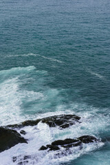 view of rocks hit by cantabrian sea with waves on moody day in northern spain