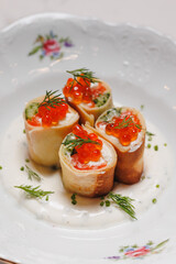 Appetizing pancake roll with salmon, cucumber and red caviar