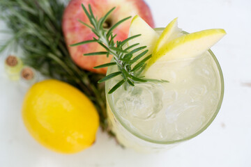 Refreshing apple and rosemary cocktail with lemon and ice in a glass