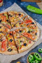 Hot tasty traditional various italian pizzas with salami, meat, cheese, onion, mushroom, tomatoes greens on a dark background