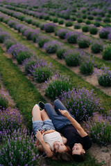 young couple in love man and girl on a walk on the street in nature under the open sky hugging and kissing. Lavender field with purple flowers for a romantic couple of people in love