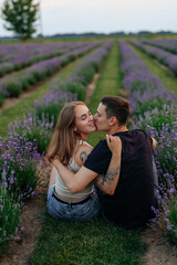 young couple in love man and girl on a walk on the street in nature under the open sky hugging and kissing. Lavender field with purple flowers for a romantic couple of people in love