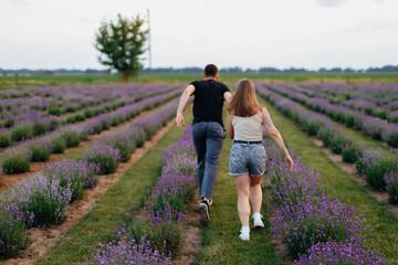 young couple in love man and girl on a walk on the street in nature under the open sky hugging and kissing. Lavender field with purple flowers for a romantic couple of people in love