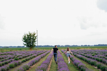 young couple in love man and girl on a walk on the street in nature under the open sky hugging and kissing. Lavender field with purple flowers for a romantic couple of people in love