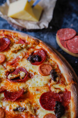 Hot tasty traditional various italian pizzas with salami, meat, cheese, onion, mushroom, tomatoes greens on a dark background