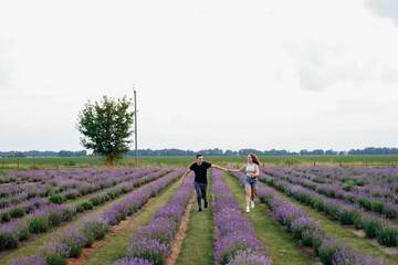 young couple in love man and girl on a walk on the street in nature under the open sky hugging and kissing. Lavender field with purple flowers for a romantic couple of people in love