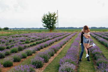 young couple in love man and girl on a walk on the street in nature under the open sky hugging and kissing. Lavender field with purple flowers for a romantic couple of people in love