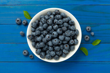 Bowl with fresh bright blueberries on wooden background,top view