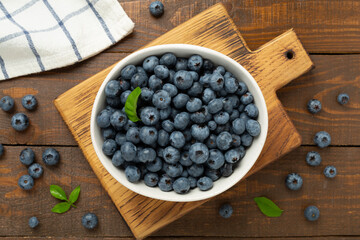 Bowl with fresh bright blueberries on wooden background,top view