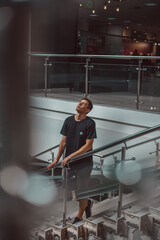 Handsome young man of European appearance in a black T-shirt in a shopping center on the street