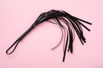 Black whip on color background, top view. BDSM concept