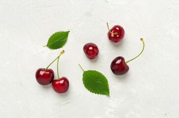 Fresh cherries in bowl on concrete background, top view