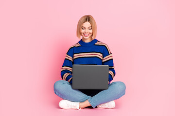Young woman with stylish bob hair using laptop against pink background