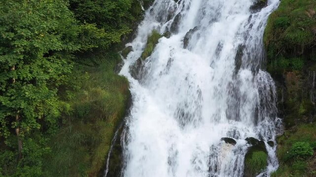 Flowing Majesty: Stunning Cascade Over Rocks Framed by Green Grass