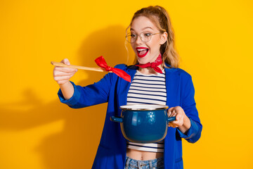 Young Woman Holding a Pan and Spoon in Stylish Fashion Against a Bright Yellow Background