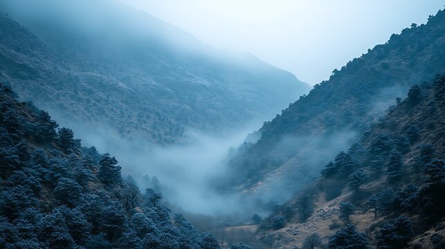 A beautiful misty mountain scene with fog creeping over rolling hills, and soft clouds drifting across the sky.