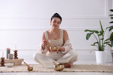 Woman with singing bowls on floor indoors