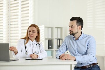 Man having consultation with cardiologist at desk in clinic