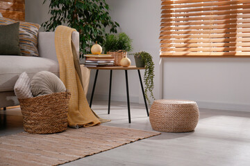 Stylish living room interior with comfortable sofa and wicker pouf