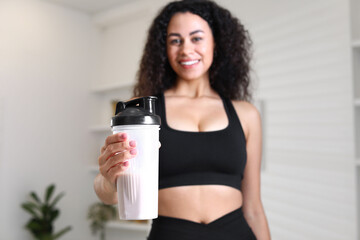 Beautiful woman with protein shake at home, selective focus