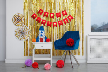 Bright pinata in shape of rocket and party accessories in festive decorated room