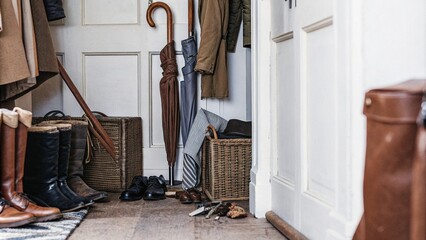 Entryway with organized coats, hats, and shoes on a vintage rug and wooden floor, evoking a rustic and inviting atmosphere