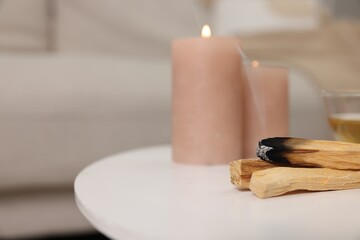 Palo santo sticks and burning candles on white table indoors, space for text
