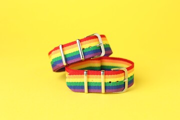 Two wristbands in LGBT colors on yellow background, closeup