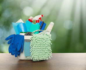 Different cleaning products in basket on wooden table outdoors. Space for text