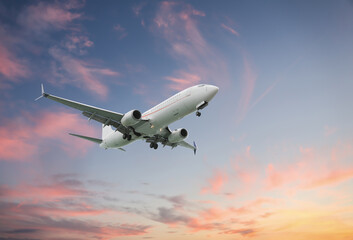 Airplane flying in beautiful sky with clouds at sunset